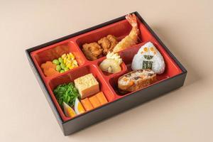 arroz de sushi inari envuelto en tofu seco con camarones fritos y pollo frito en un juego de bento - estilo de comida japonesa foto