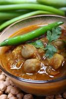 Indian spicy chana masala with raw chickpeas and green chilli topping photo