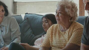 Two women a man and a girl sitting on sofa watching television whilst girl is bored video