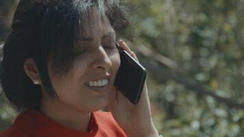 femme debout devant un arbre appelant avec un smartphone video