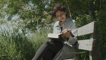 vrouw zittend op een houten bankje in het land een boek lezen video