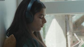 Chica con auriculares sentado en la esquina mientras escribe en el teléfono inteligente video