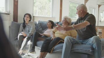 Two women a man and a girl sitting on sofa discussing whilst watching television video