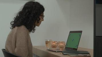 mujer en la mesa tiene videollamada en una computadora portátil con pantalla verde video