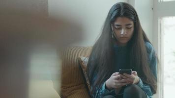 Girl sitting in corner looks at smartphone video