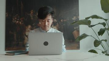 Man sits and uses laptop and woman joins him whilst answering phone call video