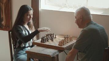 Mädchen erklärt einem Mann, der am Tisch sitzt, wie man Schach spielt video