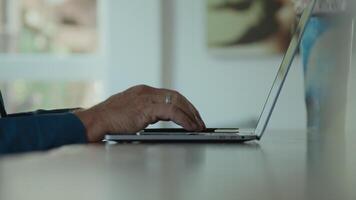 Hands of man typing on keyboard of laptop and man nods video