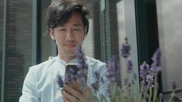 Hombre sentado afuera iniciando videollamada con smartphone video