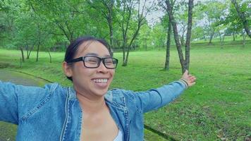 una turista feliz mirando al cielo con los brazos en alto disfrutando de la naturaleza en el bosque. estilo de vida de vacaciones. video