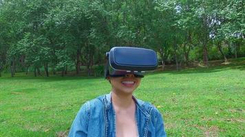 donna felice che indossa occhiali vr-auricolare della realtà virtuale nella foresta e godersi la natura in una soleggiata giornata estiva nel giardino primaverile. concetto di tecnologia moderna. video