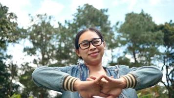 retrato de uma mulher de óculos, olhando para a câmera com uma carinha sorridente em pé no meio da natureza no jardim primavera. conceitos de viagens e felicidade. video