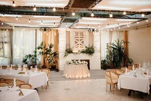 the presidium of the newlyweds in the banquet hall of the restaurant is decorated with candles and green plants photo