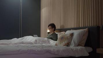 Man in bed having online conversation on laptop video