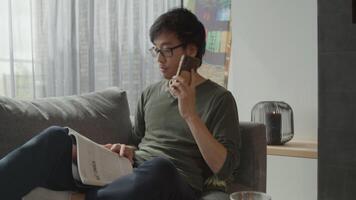 Man in living room reads and answers call on mobile phone video