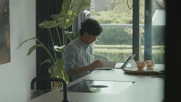 homem escreve no notebook e assiste no laptop video