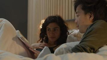 donna e uomo che leggono una rivista insieme mentre sono a letto video