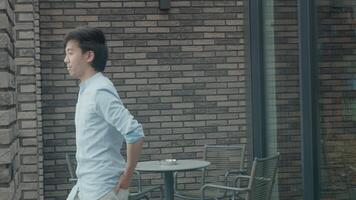 Hombre saludando y sonriendo mientras está de pie en la terraza video