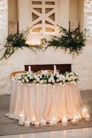 the presidium of the newlyweds in the banquet hall of the restaurant is decorated with candles and green plants photo