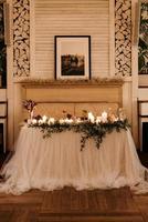 el presidium de los recién casados en el salón de banquetes del restaurante está decorado con velas y plantas verdes foto