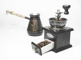 Coffee beans in a small box of wooden coffee grinder and a cezva on the background on white background photo