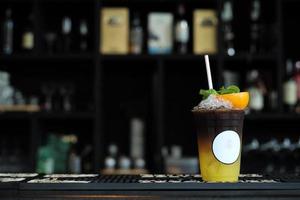 Cup of black coffee mixed with orange juice with white blank label on the glass photo