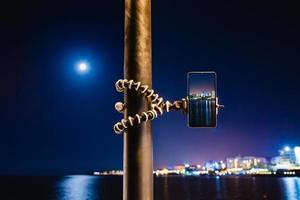 Using a smartphone on a foldable tripod with long exposure of the sea at night photo