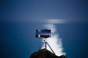 usando un teléfono inteligente en un trípode con larga exposición al mar por la noche foto