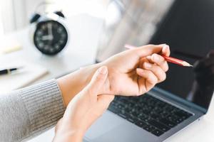 mujer de cerca sosteniendo su dolor de muñeca por usar la computadora durante mucho tiempo. concepto de síndrome de oficina. foto