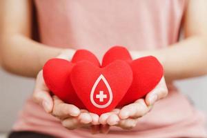 Woman hands holding red heart with blood donor sign. healthcare, medicine and blood donation concept photo