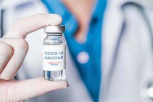 doctor or scientist in laboratory holding a Coronavirus Vaccine in glass bottle. Covid-19 corona virus treatment concept. photo