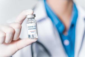 doctor or scientist in laboratory holding a Coronavirus Vaccine in glass bottle. Covid-19 corona virus treatment concept. photo
