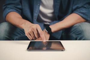 cerca de joven con tableta en el sofá. búsqueda, navegación, compras en línea, redes sociales. foto