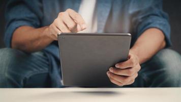 Close up of young man using tablet on the sofa. searching, browsing, shoping online, social network. photo