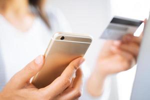 mujer usando un teléfono inteligente con una tarjeta de crédito. compras en línea, finanzas, comerciales en línea.