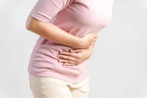 mujer joven que sufre de un fuerte dolor abdominal sobre fondo blanco. gastritis, período, menstruación. foto