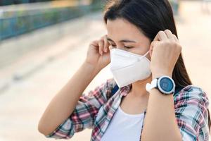 Asian woman wearing N95 mask to protect pollution PM2.5 and virus. COVID-19 Coronavirus and Air pollution pm2.5 concept. photo