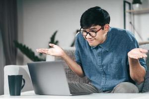 Confused clueless man using laptop computer for Video conference call shrugging shoulders making no idea, whatever gesture I don't know, who cares Concept photo