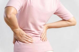 mujer joven que siente dolor en la espalda sobre fondo blanco. concepto sanitario y médico. foto