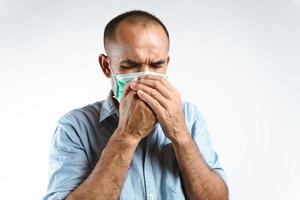 Man wearing face mask sneezing or coughing over his hand to prevent spread the virus COVID-19 or Corona Virus on white background. photo