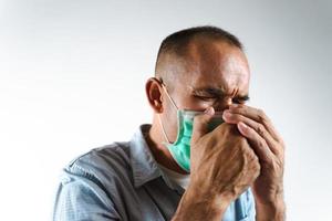 Hombre con mascarilla estornudando o tosiendo sobre su mano para evitar la propagación del virus covid-19 o coronavirus sobre fondo blanco.