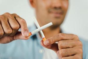 mano de hombre sosteniendo cigarrillos cruzados. concepto dejar de fumar, día mundial sin tabaco. foto