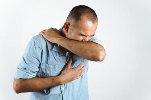 Man sneezing or coughing in his elbow to prevent spread the virus COVID-19 or Corona Virus on white background. photo