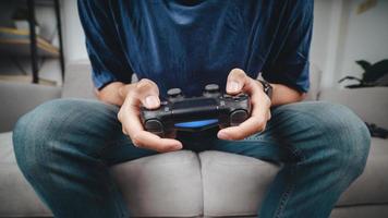 Hombre guapo joven emocionado sosteniendo controlador de joystick jugando videojuegos sentado en el sofá en casa foto