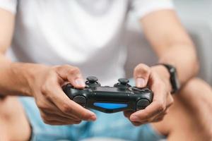 Excited young handsome man holding joystick controller playing video game sitting on the couch at home photo