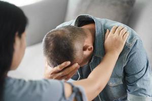 Female Psychologist, friend or family sitting and put hands on the shoulder for cheer up to mental depress man, Psychologist provides mental aid to the patient. PTSD Mental health concept photo