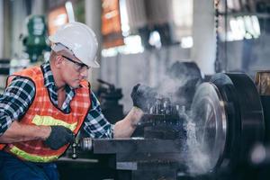 Engineer metalworker working on lathe machine photo