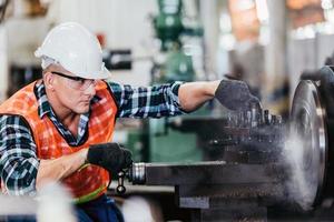 Engineer metalworker working on lathe machine photo