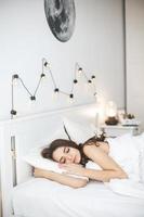 Mujer joven durmiendo pacíficamente en el dormitorio con sábanas blancas frescas