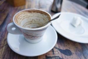 Taza blanca con sobras de café en la mesa